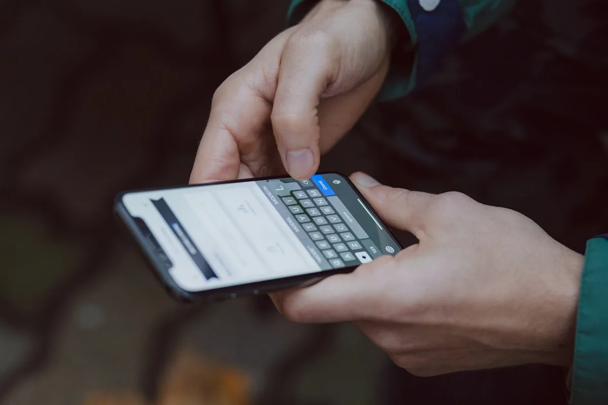 Manos sosteniendo un smartphone con teclado abierto intentando navegar una web en mobile con dificultad