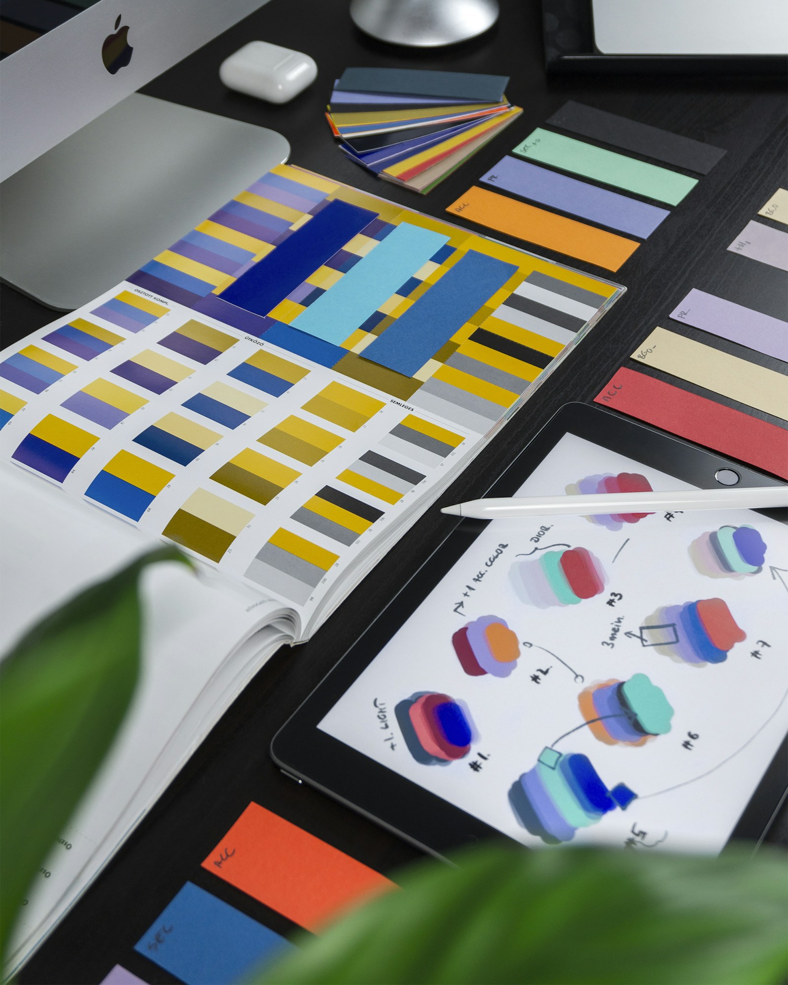 Mesa de diseño creativo con paletas de color, muestras tipográficas, iPad con bocetos y materiales de branding profesional